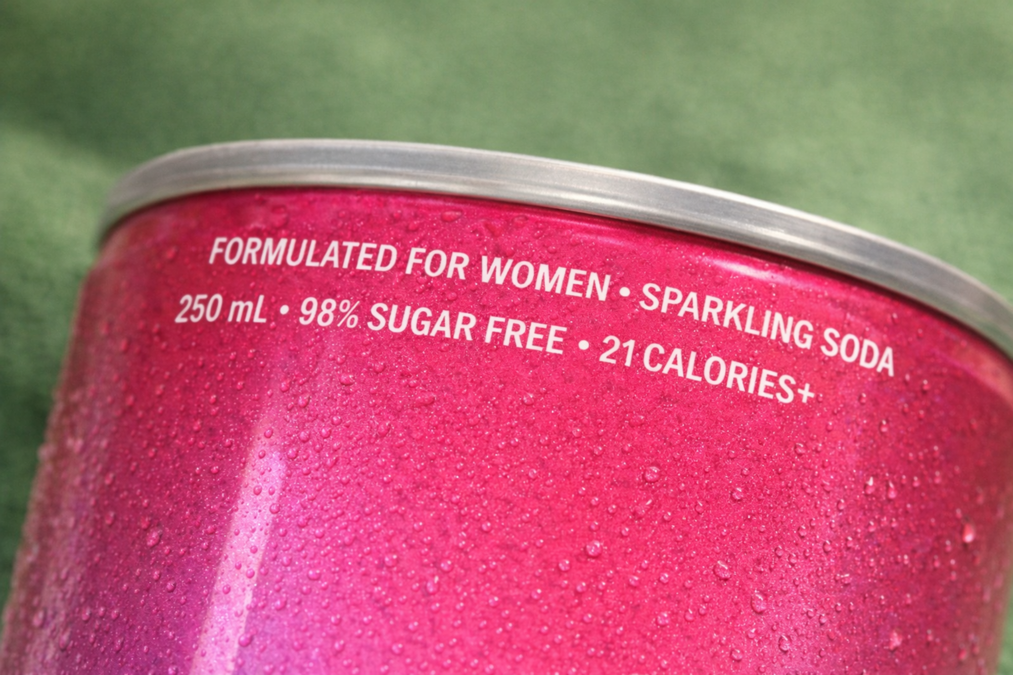 Close-up of JUNA pink sparkling soda can showing formulated for women text with water droplets